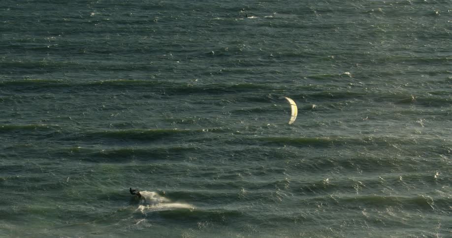Kite surfer kitesurfing on the gentle ocean waves in the evening