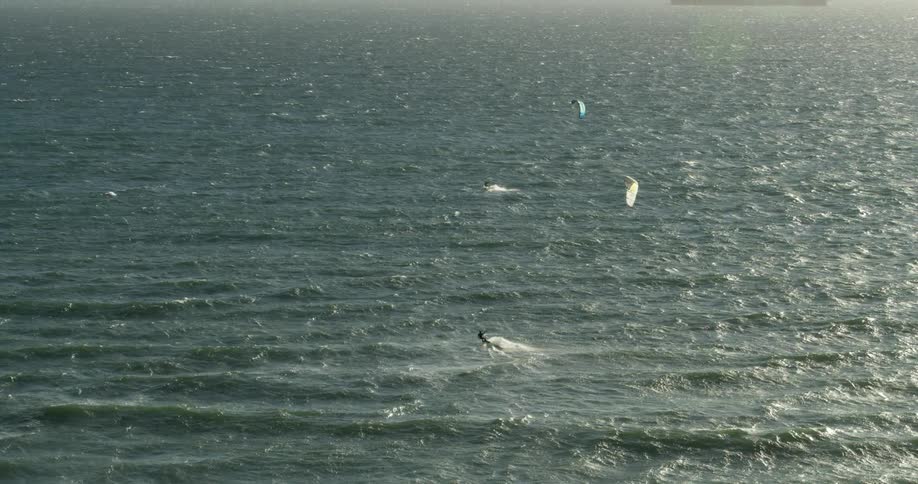 A person kitesurfs in the open ocean with a large ship in the background