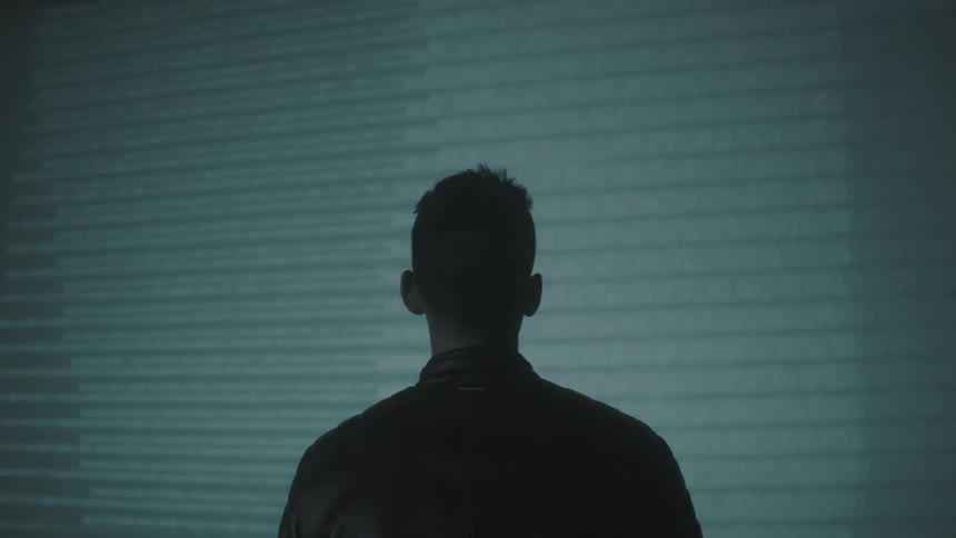 A man is watching lights flash on a wall from a projector