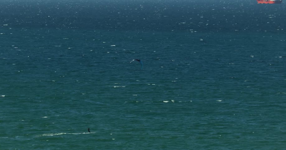 Kiteboarder is pulled across the water by his kite in the ocean