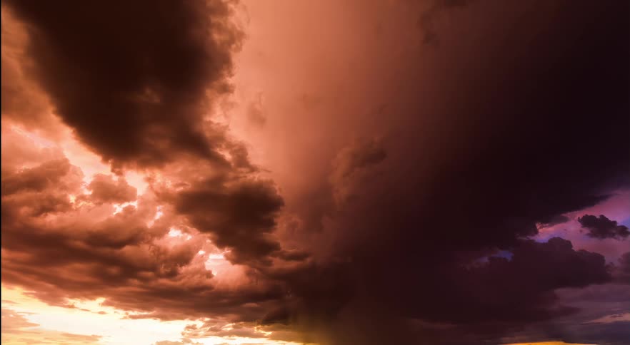 Strange dark storm clouds with an orange and purple glow move over the land as lightning flashes