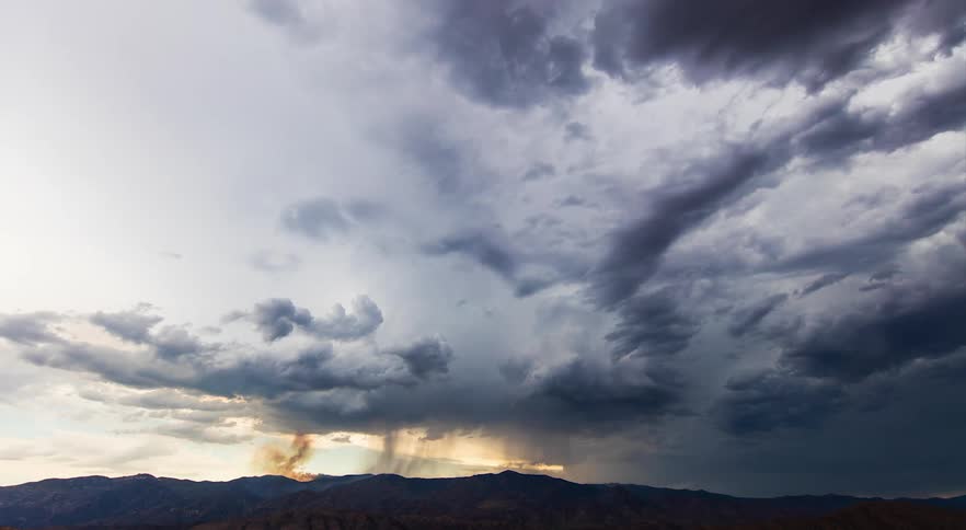 Time lapse of storm clouds and a wildfire moving over the landscape