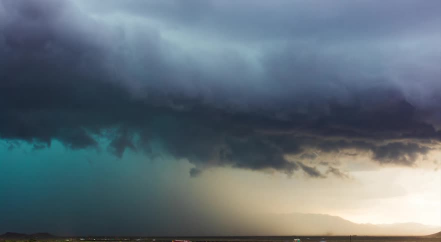 Time lapse of storm cloud rolling across a highway in a rural area