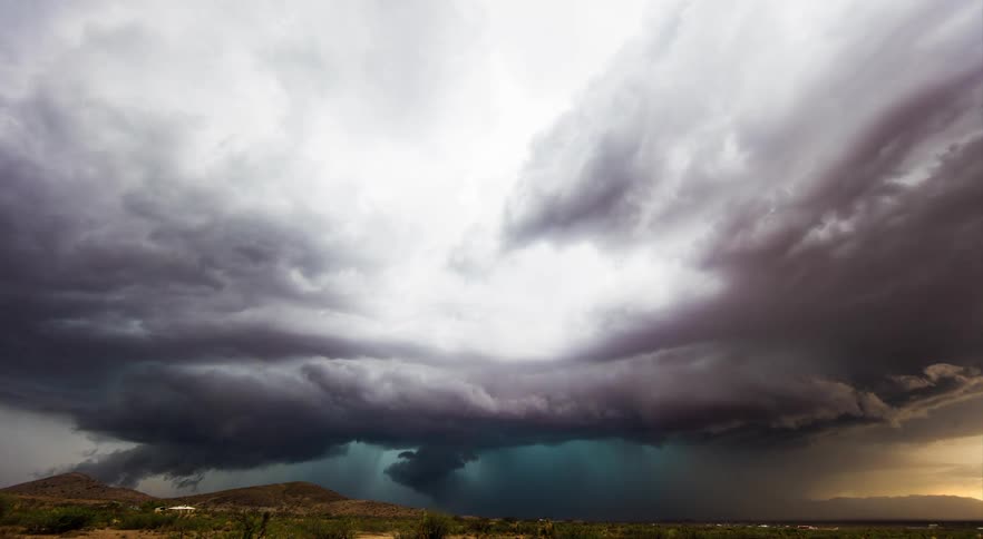 An intense thunderstorm forming over a wide desert landscape