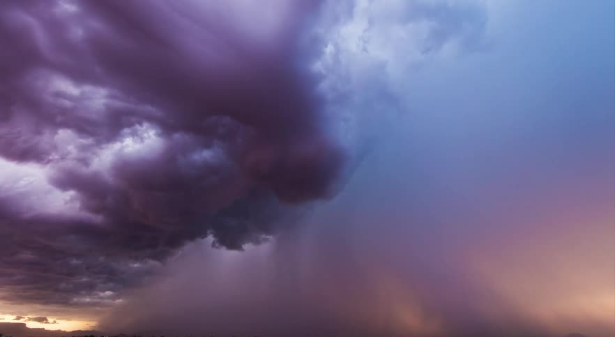 Dark storm clouds change from purple to blue gray while moving across countryside