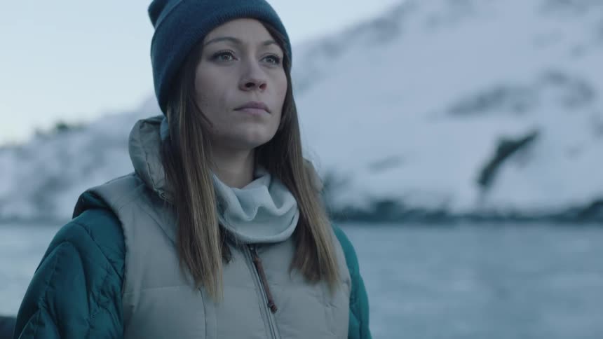 A woman in a jacket and cap lowers a map and looks around