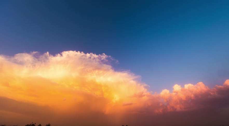 Large clouds change from yellow to red as they flow across countryside