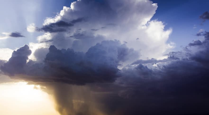 Storm front moves across plains partly obscuring mountains on the horizon