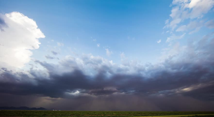 Flowing storm clouds are bringing in a dust cloud over a prairie