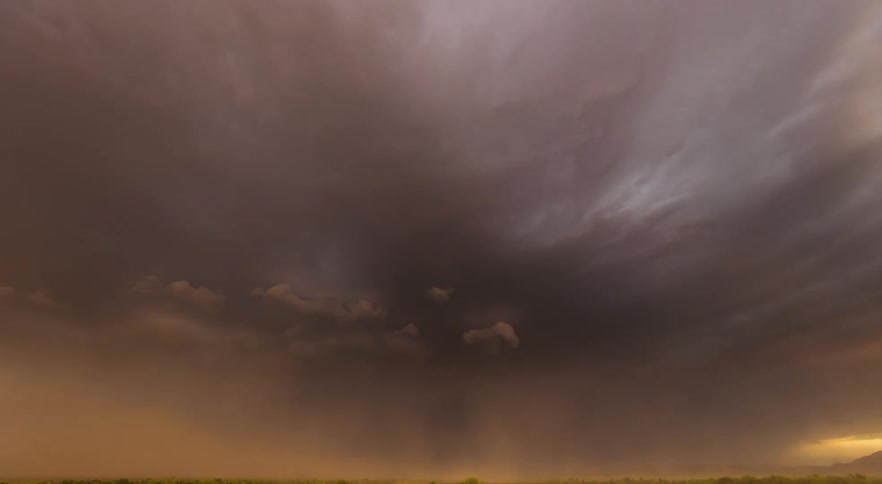 A wide shot of a monsoon thunderstorm at sunset with dust blowing