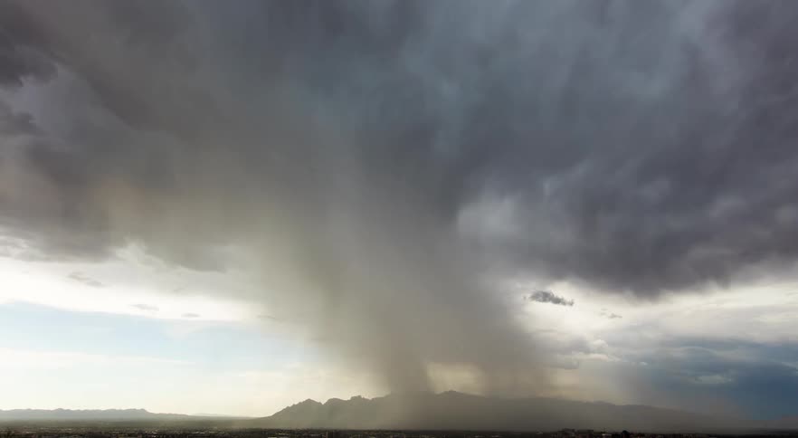 Dark ominous storm clouds move and rotate across the sky and dump rain down on a community