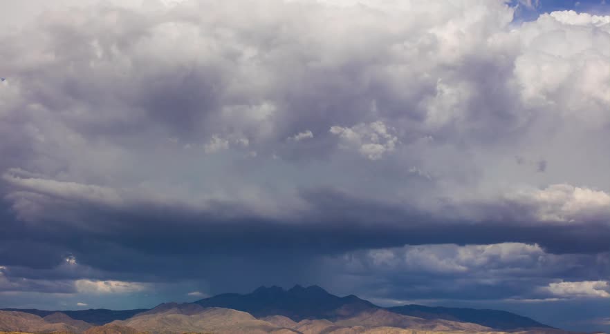 Storm clouds are flowing and pouring rain over mountain wilderness
