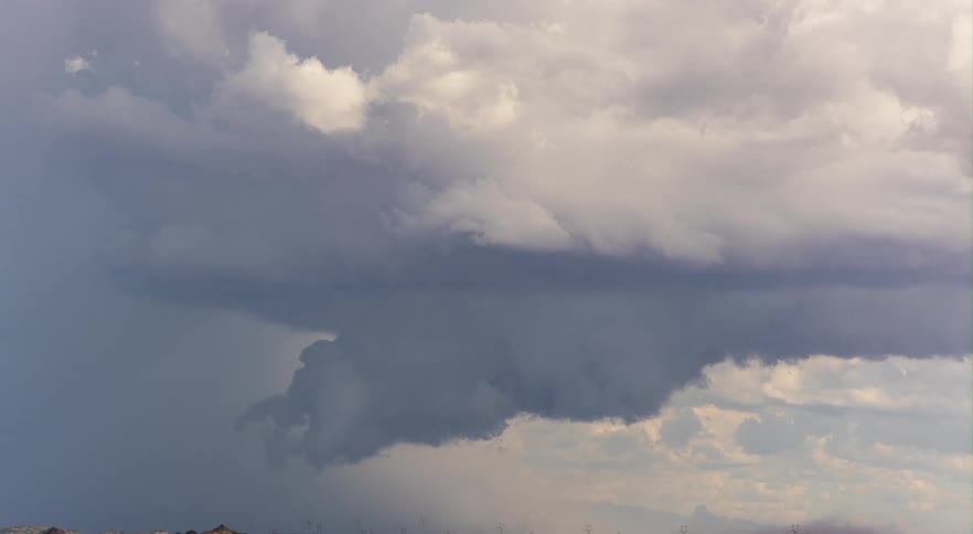 A tornado storm forming in the distance over a flat meadow