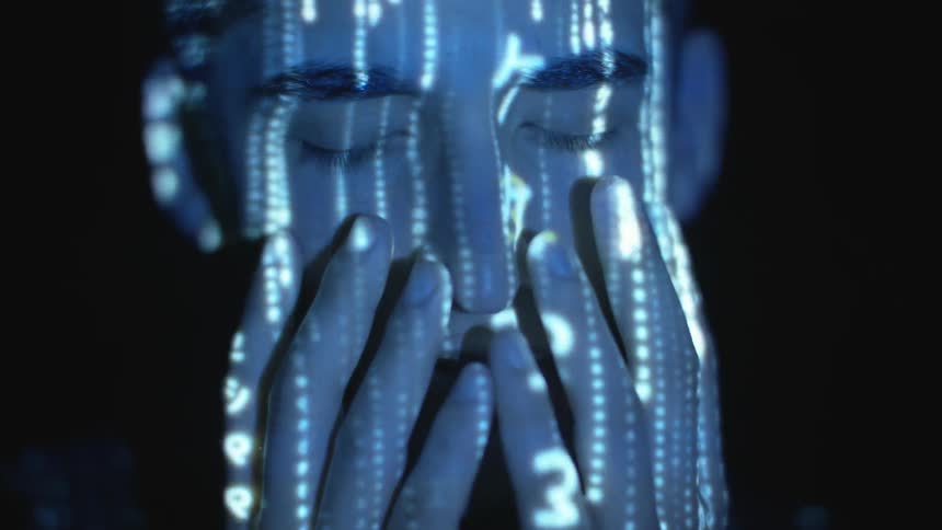 A man moves his hands down his face as lights are projected on his skin