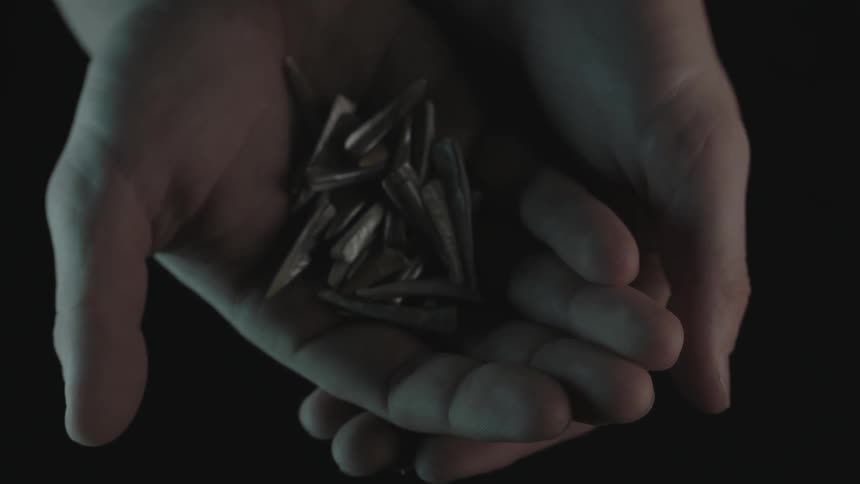 Hands opening to reveal pointy objects in the palm