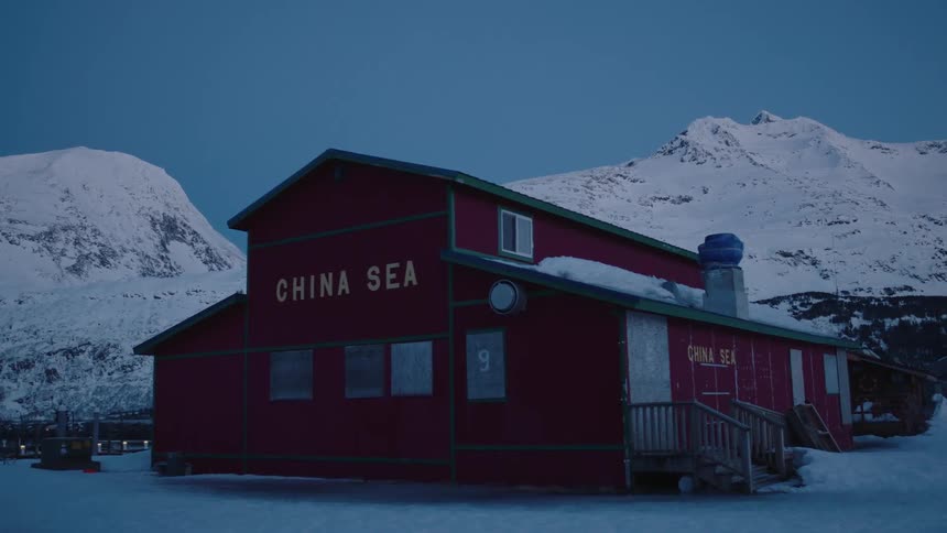 A building is red near some snow covered mountains