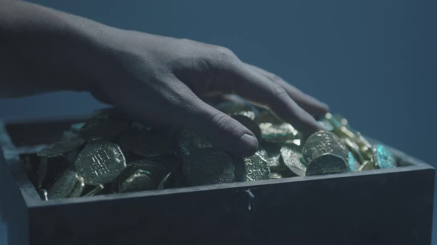 A person runs their hands over gold coins