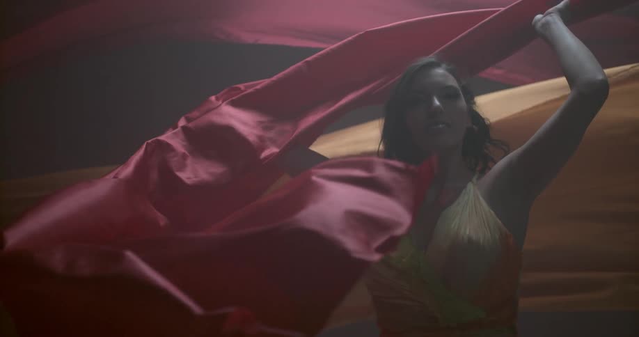 A woman is dancing twirling long sheets