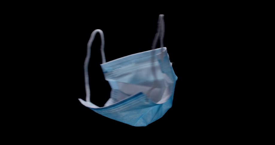A medical face mask offers protection from a virus while rotating in the darkness of a studio