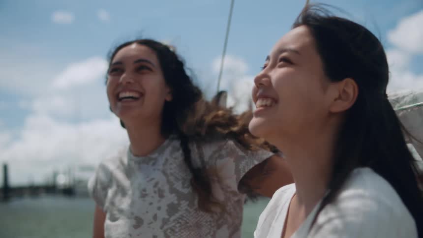 Women sitting on boat on water on windy day smile as they interact