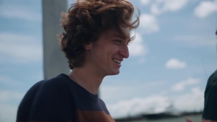 Two friends laugh while standing on a pier along the waterfront