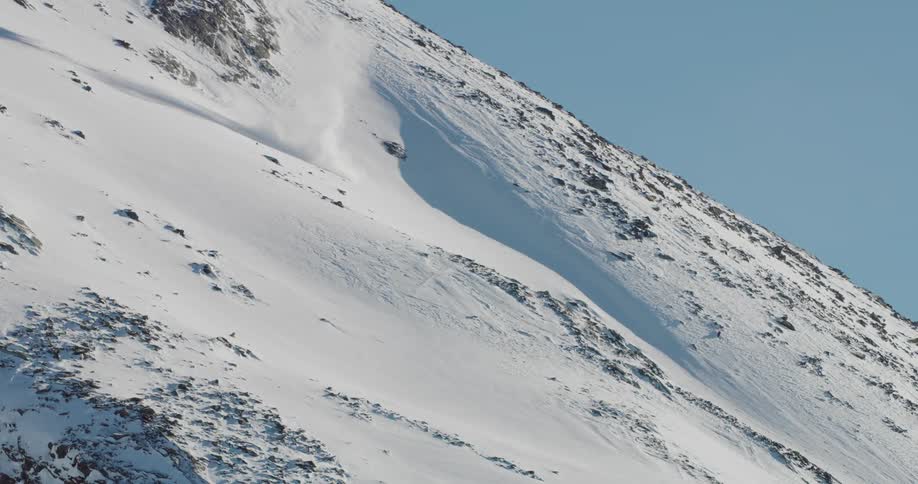 A whitish hill rises up before the viewer with some parts of it exploding in a violent eruption the hill is made up of a lightcolored rock or ash with deep cracks and fissures running through it