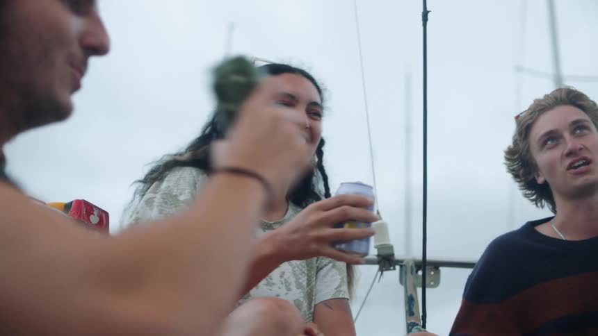 A group of friends drinks from cans on the boat on a cloudy day