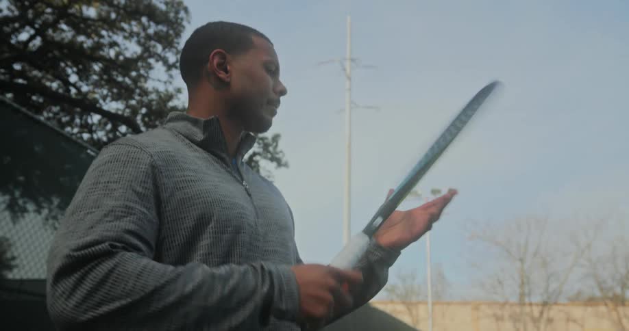 A man spins a tennis racket around on the court
