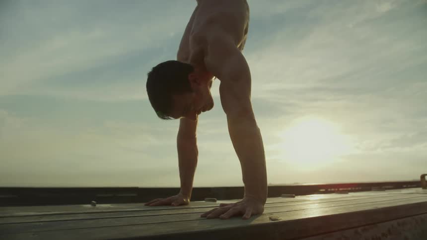 A man lifts himself into a handstand while working out on the beach