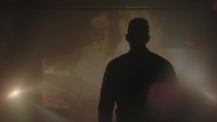A man watches a fire projected on a screen