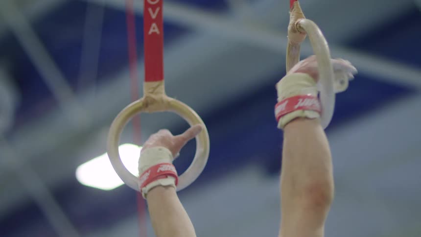 Close up of the hands of a man holding onto gymnastic rings
