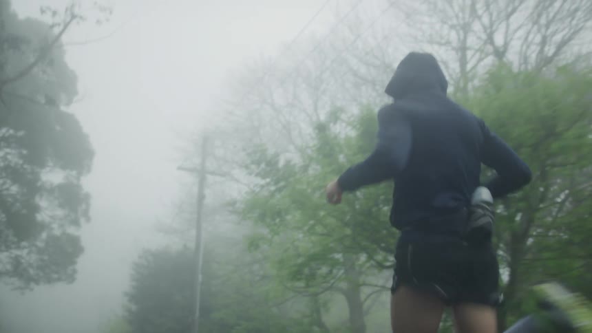 Man with black hoodie and black shorts jogis in the fog