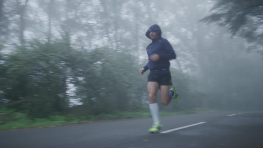A woman running on a paved road on a foggy day