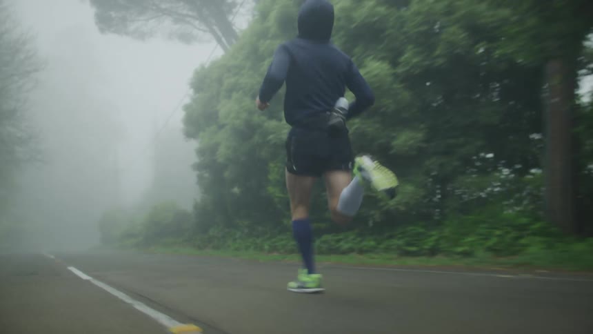 Jogger runs along side of road on foggy day