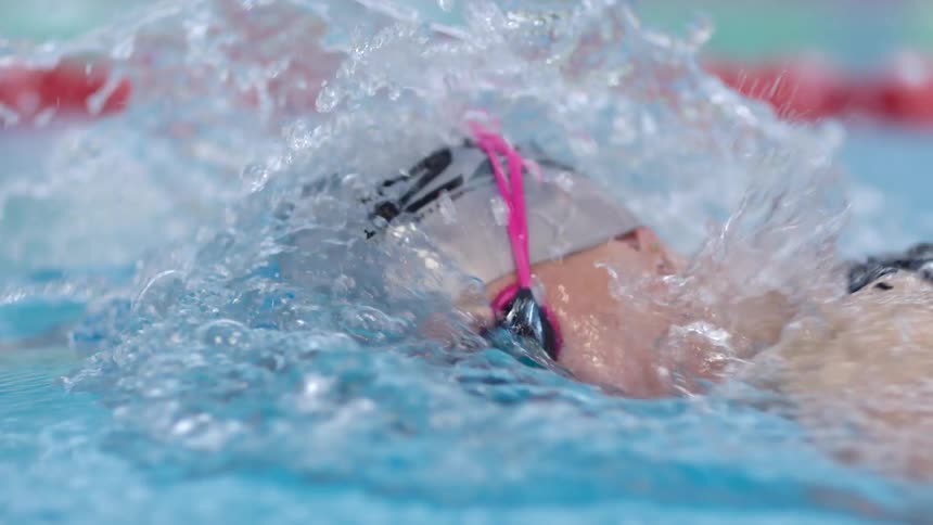 A competitive swimmer paddles down the pool lane