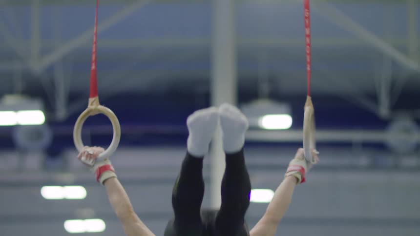 A gymnast is doing flips as he works out on the rings