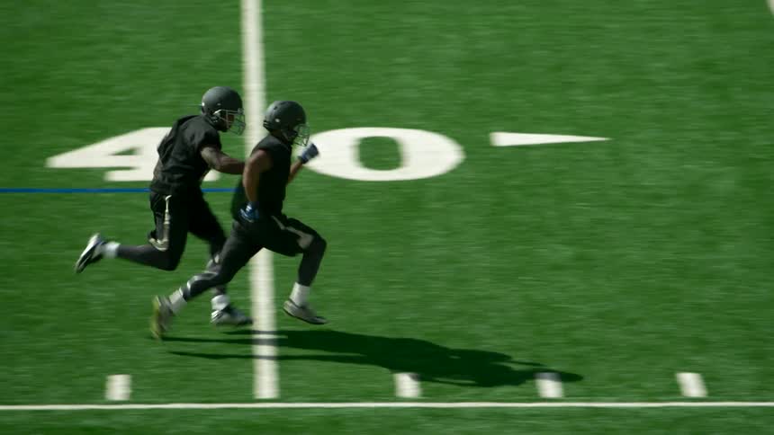 Two football players are running across the field