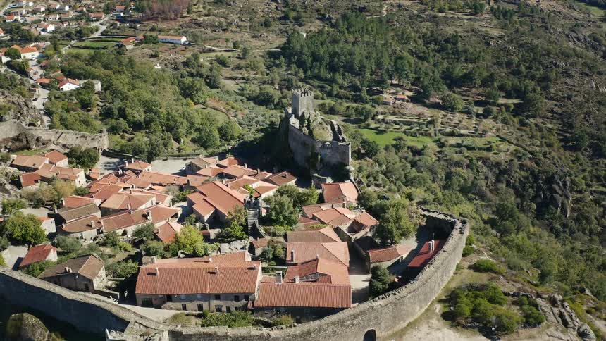 An aerial view of buildings and a stone wall in a village