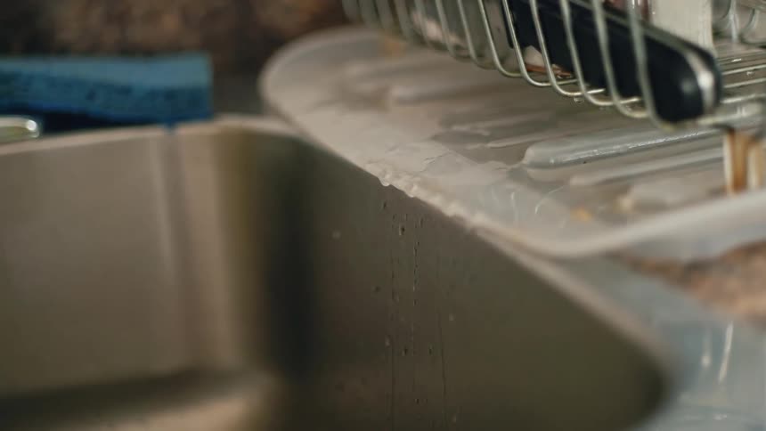 Close up of water dripping from drying dishes on the kitchen sink at home