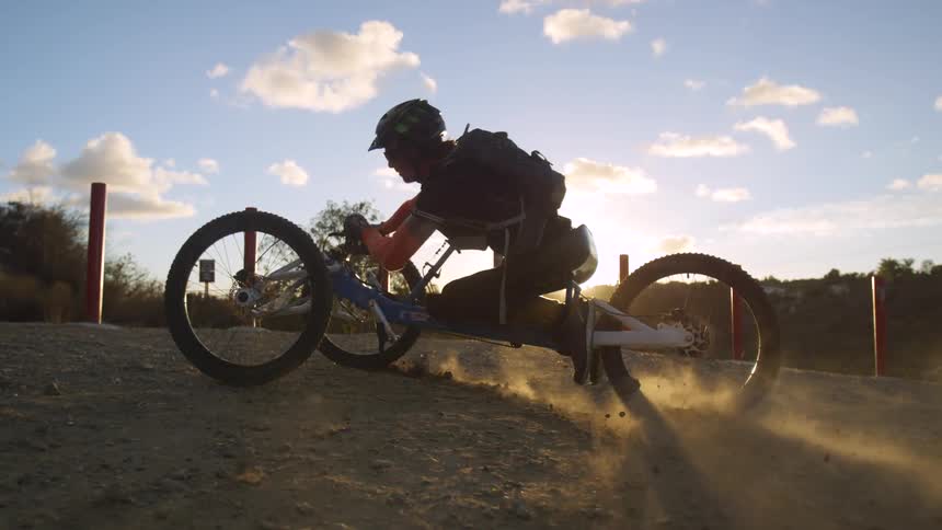 Tracking a man riding an all terrain tricycle or trike at sunset