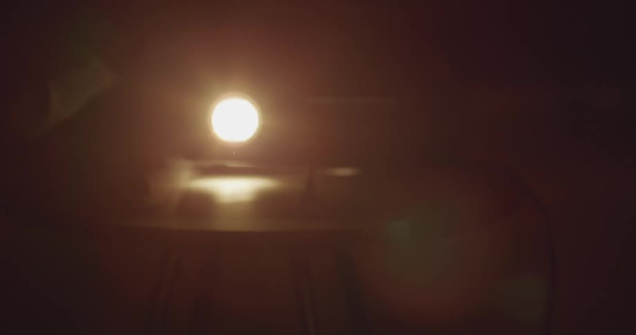In almost total darkness a projector light sitting on a desk slowly flashes on and off