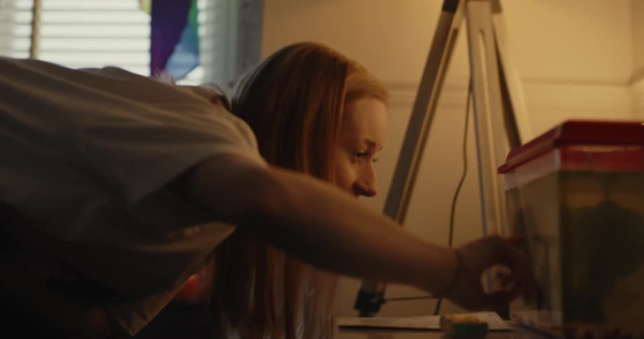 A girl taps a fish tank in her bedroom