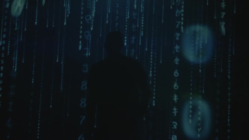 A man stands in a room with lines of code raining down