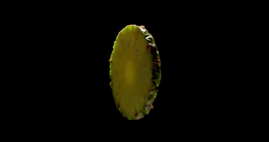 Close up of a yellow and delicious slice of pineapple spinning around with black background