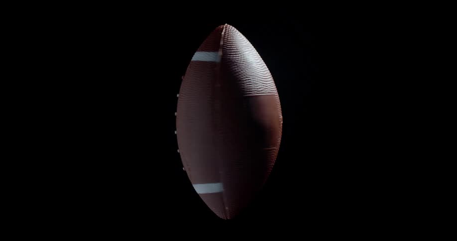 American football rotating vertically while flying through the air on its way to a field goal with a black background