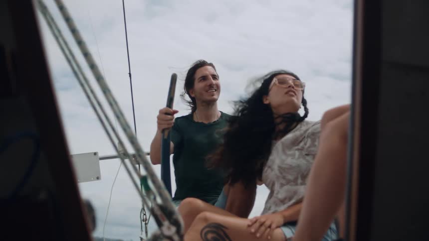A man and woman are in a helicopter that is flying in the air and the man is talking to someone whose legs are the only body part shown