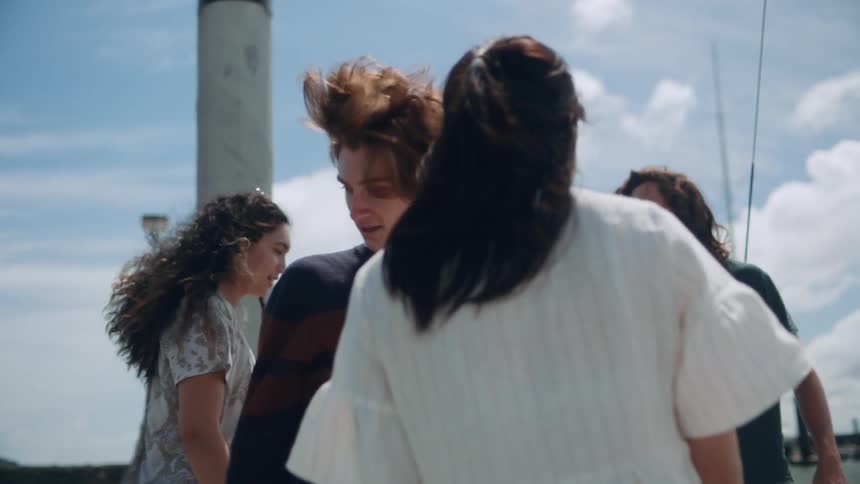 A group of friends hug when meeting up outside a boat