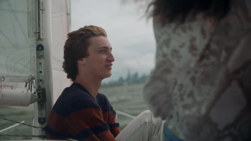 Young happy relaxed man laughs while talking to his friend on a sailboat