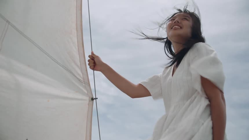 A woman smiles as she sails on a boat