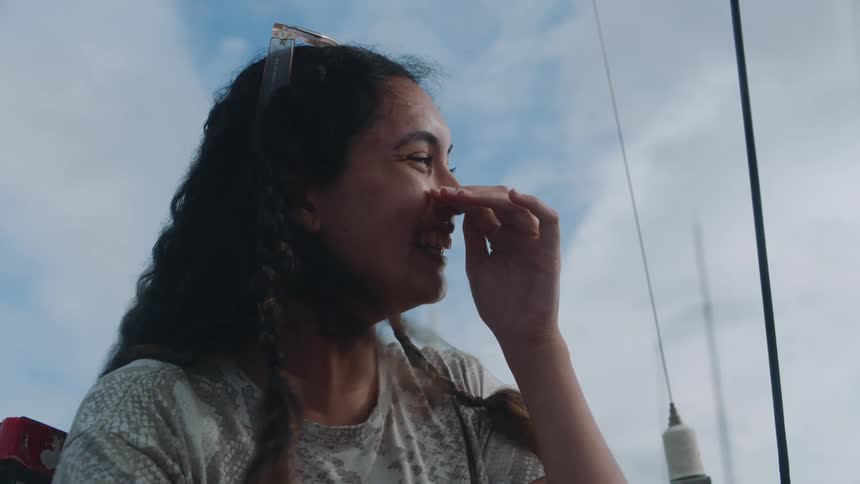 The lady is experiencing a moment of joy and happiness evident from the wide smile on her face and the sound of her laughter she uses her hand to cover her mouth perhaps out of shyness or to muffle the sound